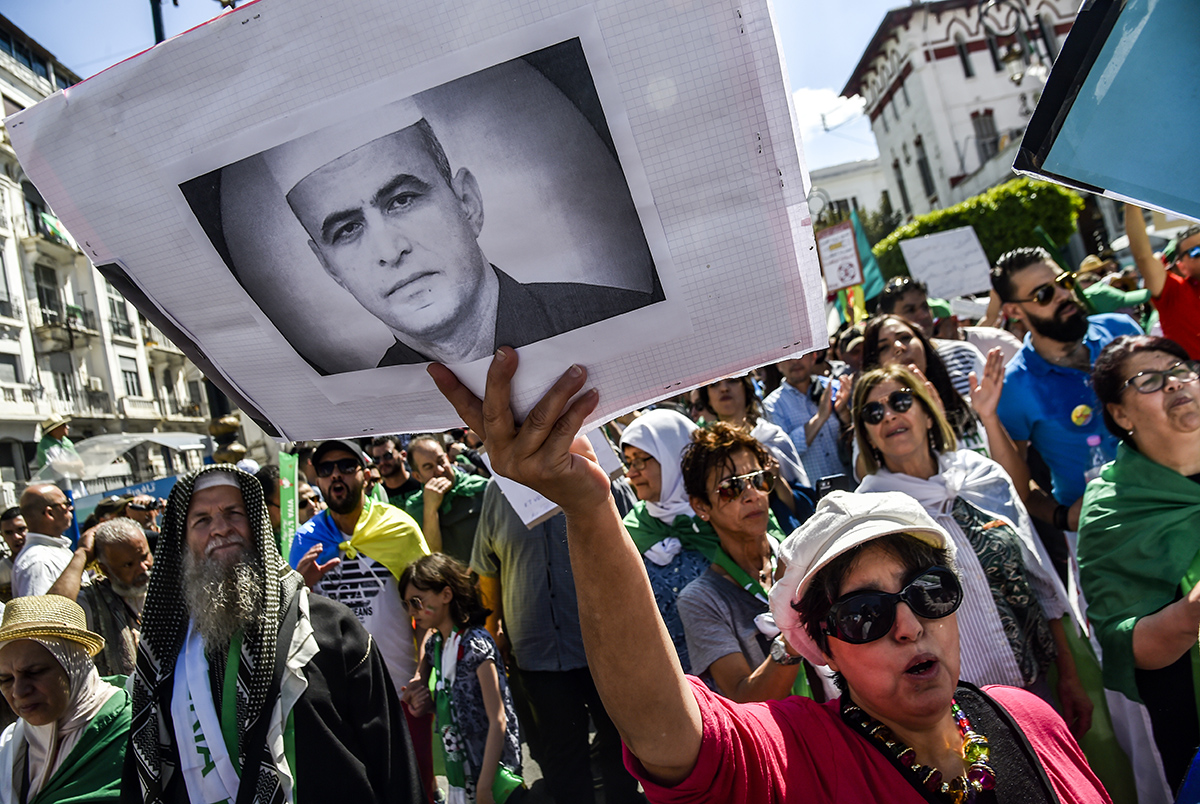 جزائرية ترفع صورة كمال الدين فخار الذي توفي الثلثاء الماضي (أ.ف.ب)