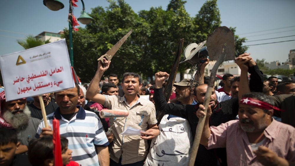 عدد من العمال يرفعون أدوات عملهم المتعطلة بسبب الحصار على غزة.jpg