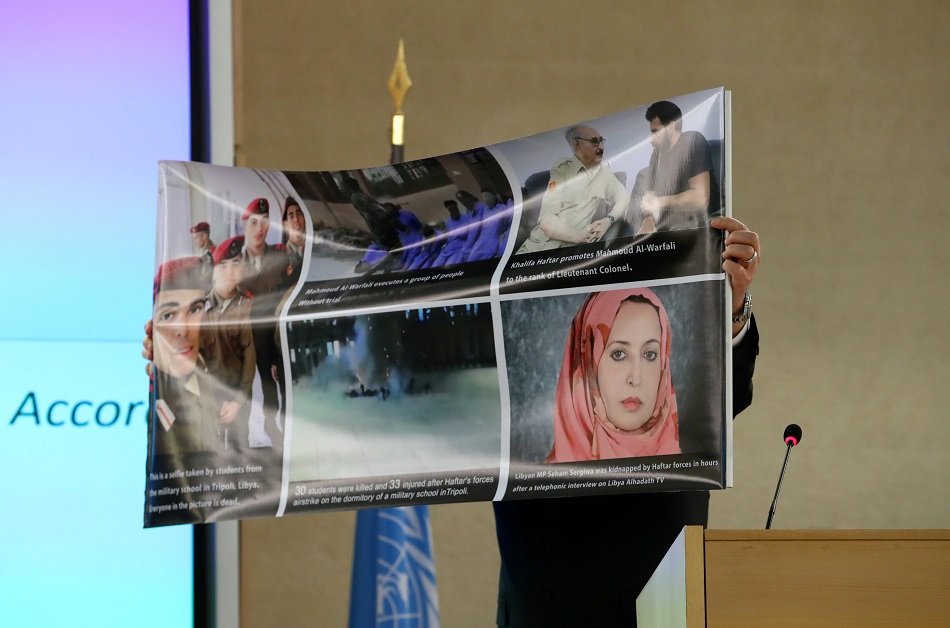 السراج يرفع لافتة تحمل صوراً أثناء تحدثه أمام مجلس حقوق الإنسان في جنيف (رويترز)