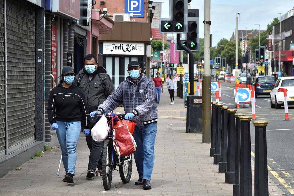 مواطنون بريطانيون يرتدون أقنعة واقية في أحد شوارع مدينة ليستر في شمال إنجلترا التي أعيد إغلاقها بسبب تجدد عدوى كورونا (أ.ب) 