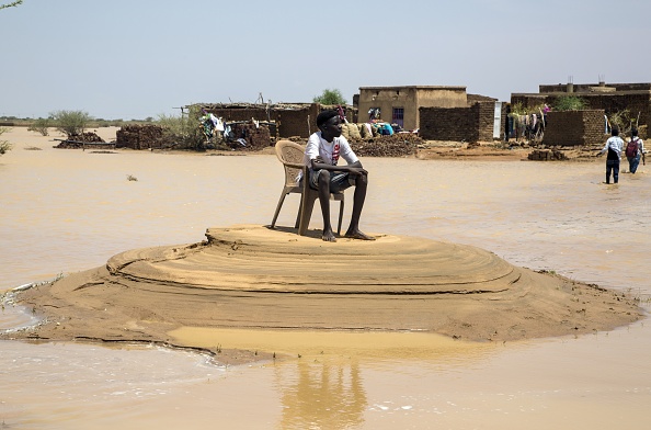 شاب يجلس وسط بقعة جافة تحيط بها مياه الفيضان (غيتي)