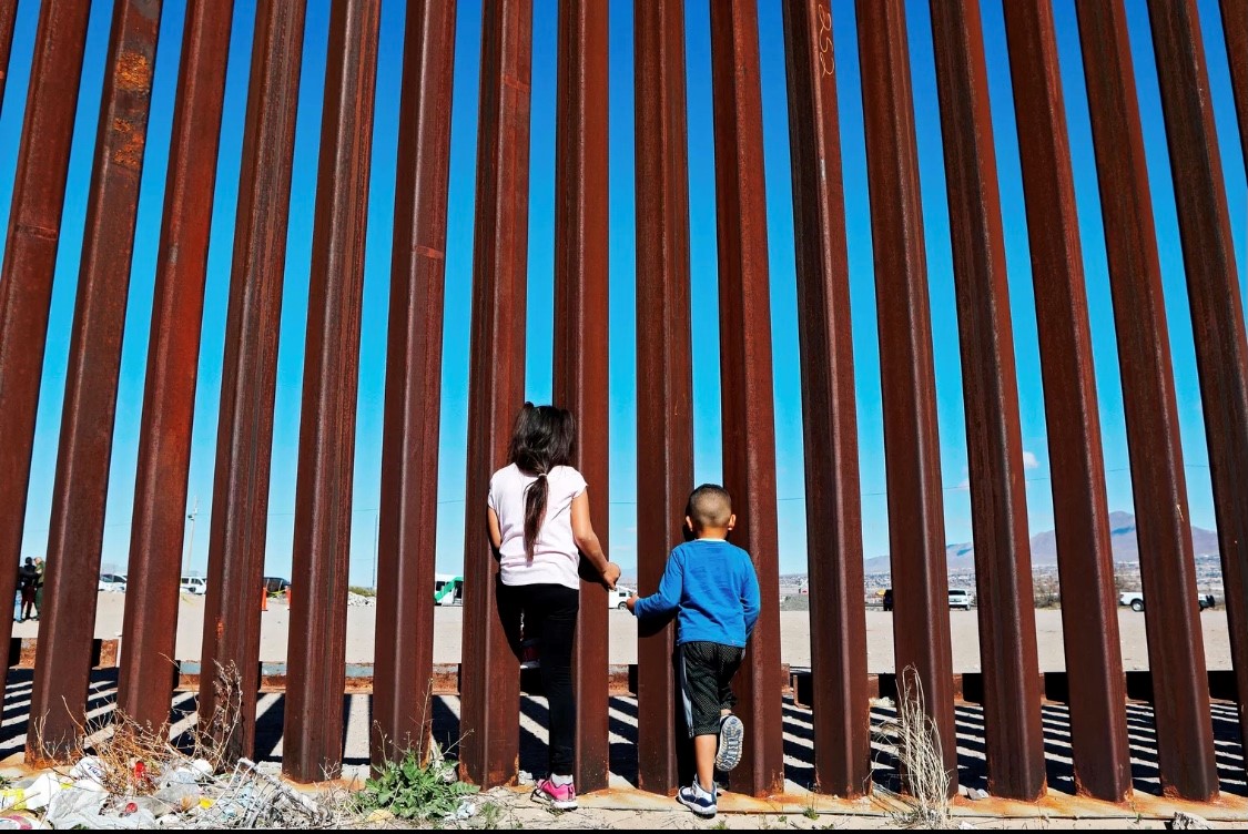 طفلان ينظران من خلال الجدار الفاصل بين الولايات المتحدة والمكسيك .(غيتي).jpg
