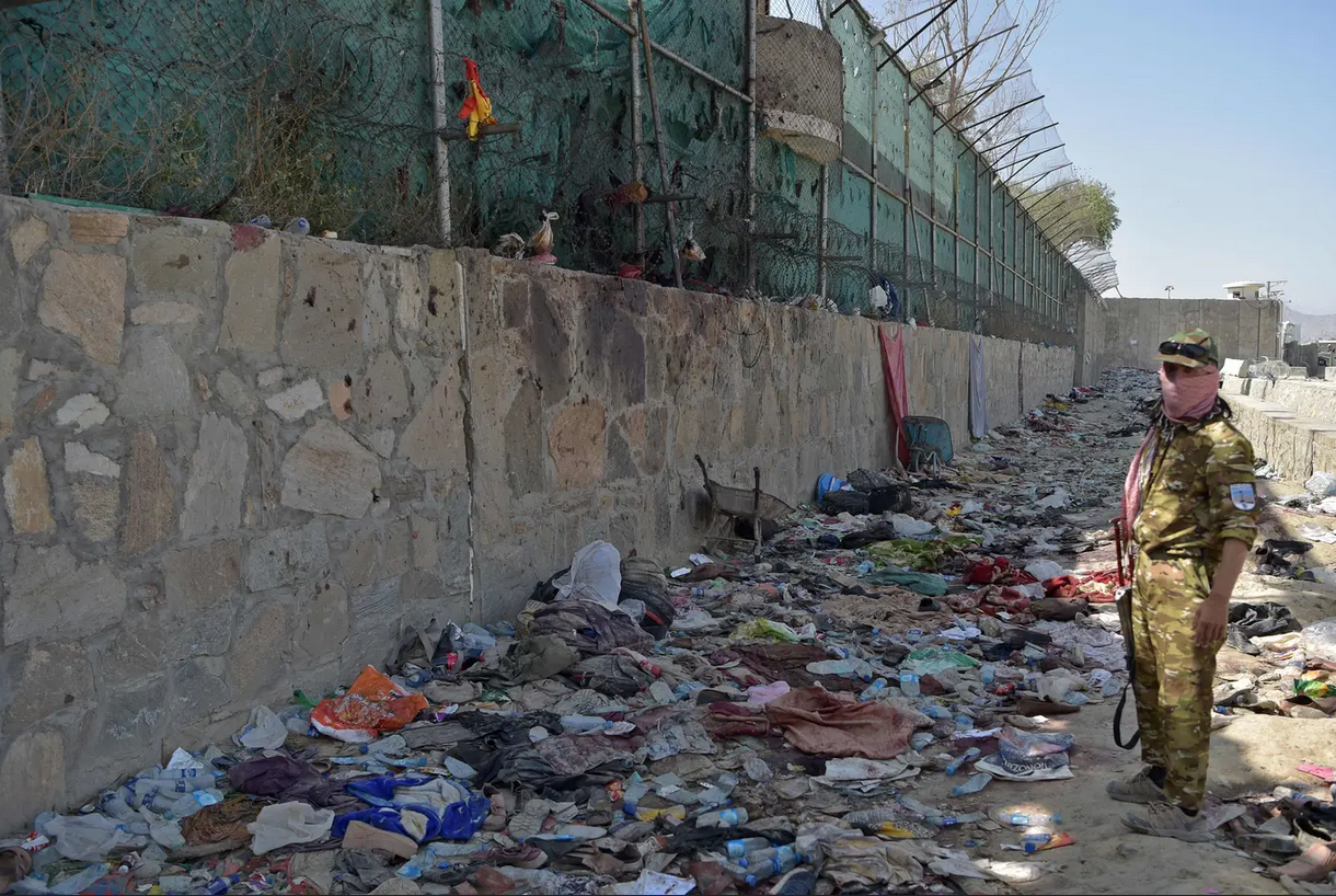 مقاتل من "طالبان" وسط الأشلاء والدمار الذي خلفه التفجير الانتحاري المزدوج في مطار كابول