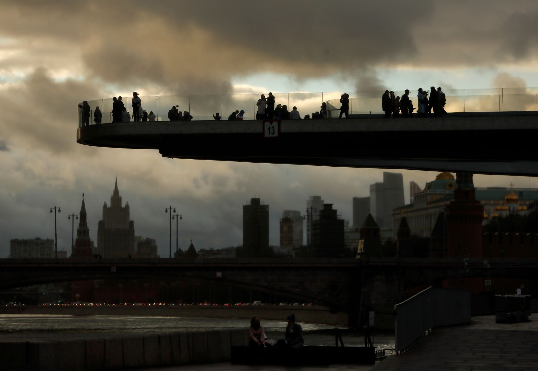مشاة على جسر معلق فوق نهر "موسكوفا" عند المغيب في موسكو 