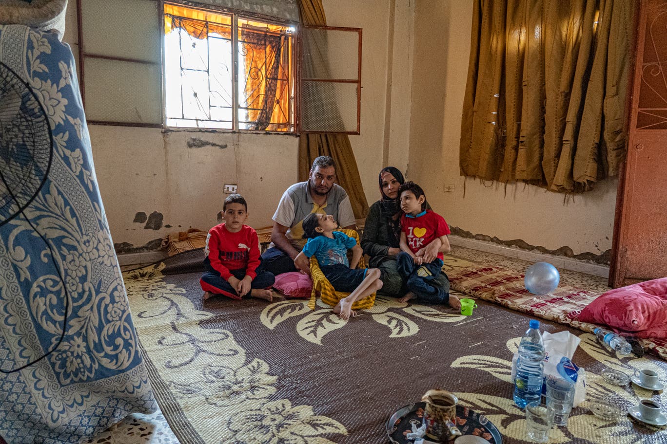 Hanan and her family sit on the floor of one of two rooms they live in 3.jpg