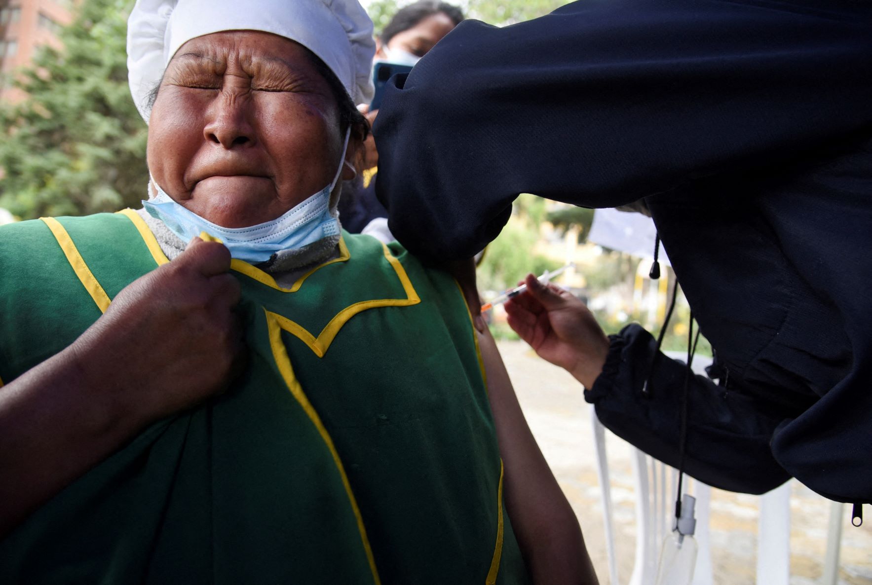 امرأة بوليفية يبدي وجهها ردّة فعلها أثناء تلقيها لقاحاً ضد مرض كوفيد، في ديسمبر 2021 