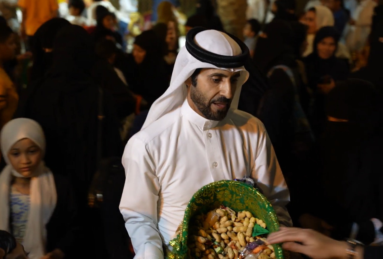 رجل يوزع حلويات القرقيعان على المارة في تاروت (اندبندنت عربية)