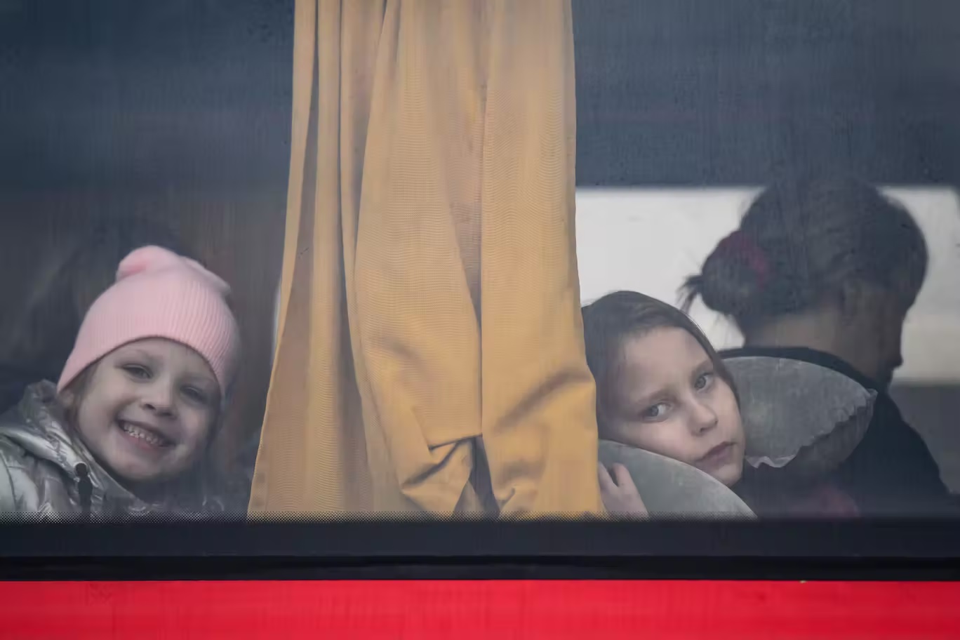 أطفال يفرون من الحرب في أوكرانيا مع عائلاتهم ينظرون من نافذة حافلة بعد عبورهم الحدود إلى بولندا (أ ب)