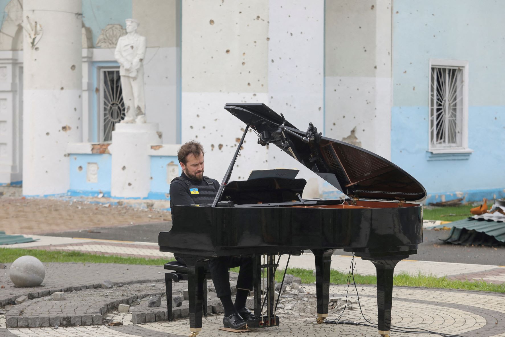 الموسيقي الليتواني داريوس مازنتاس يعزف على البيانو أثناء الغزو الروسي لأوكرانيا أمام "المبنى المركزي للثقافة" في ضاحية "إربين" بكييف، بتاريخ 26 إبريل 2022 