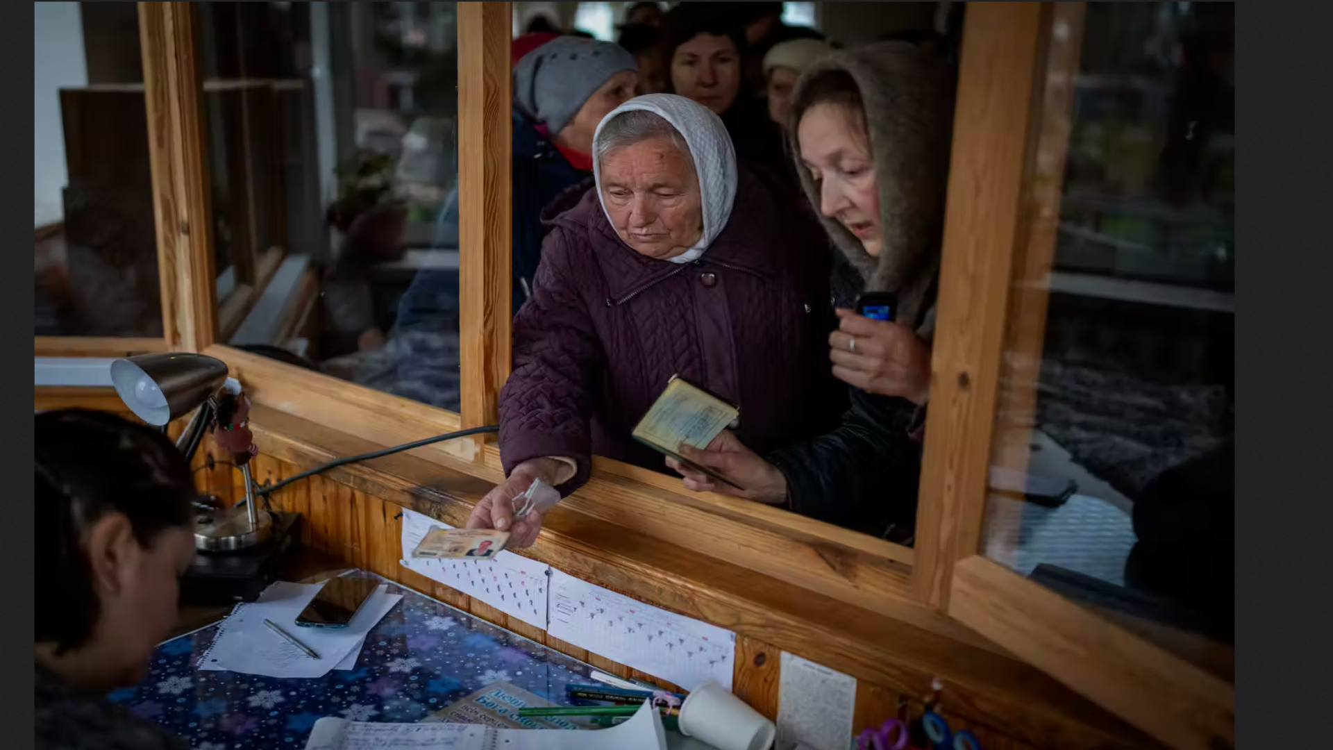 نساء أوكرانيات يظهرن بطاقات هويتهن داخل كنيسة لتلقي المعونة الإنسانية التي تبرع بها الاتحاد الأوروبي في بوتشا 