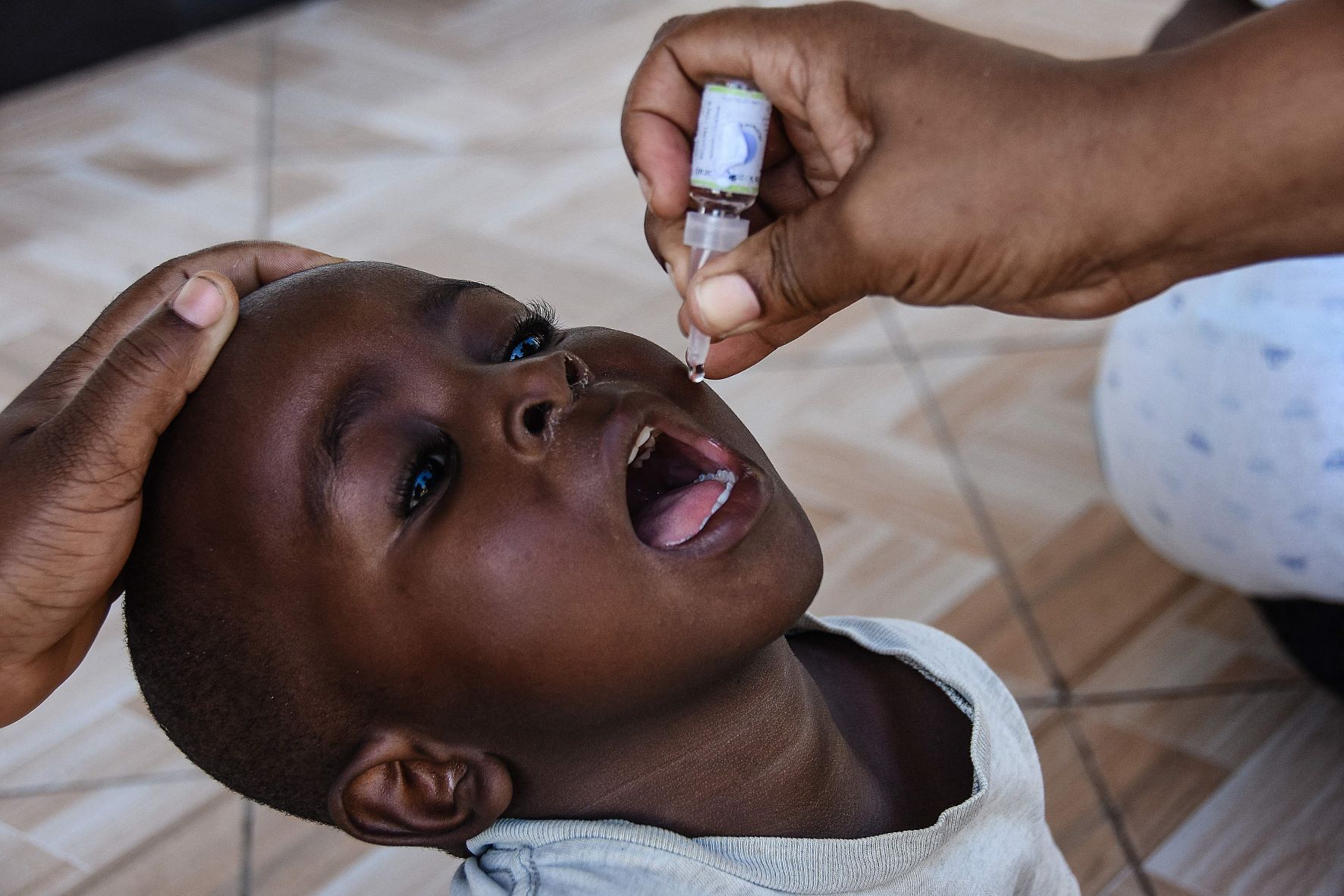 عامل صحي يعطي لقاح شلل الأطفال الفموي، خلال حملة عامة للتطعيم في "مبيزي ماكابي" قرب مدينة "دار السلام" التنزانية، بتاريخ 21 مايو 2022 