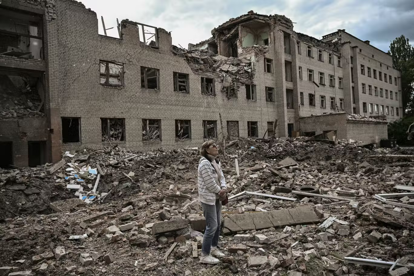 امرأة تقف قبالة بناء إداري قصفه الروس في باخموت في منطقة دونباس في شرق أوكرانيا (أ ف ب/ غيتي)