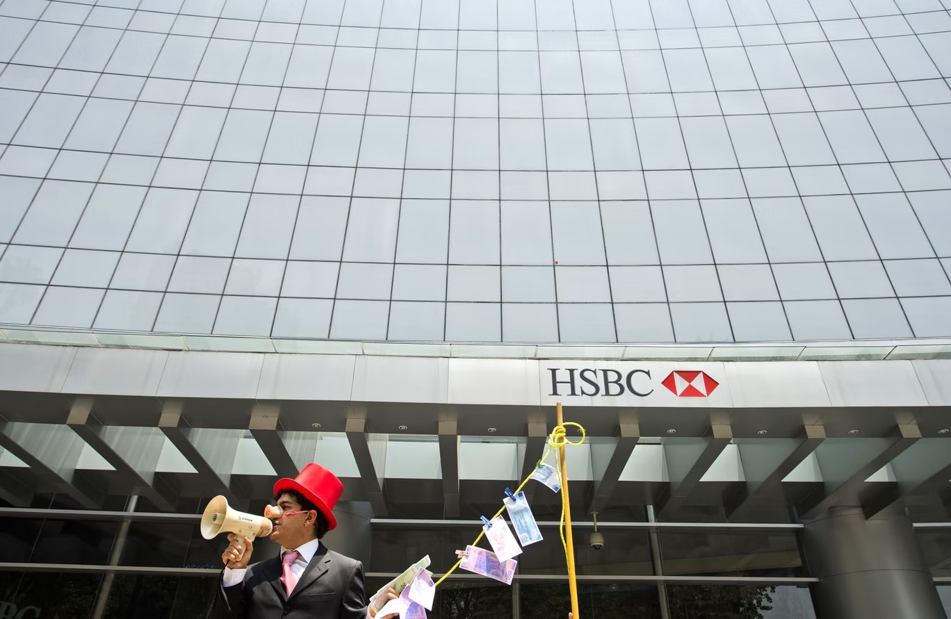رجل يرتدي أنف خنزير ويحمل أوراقا نقدية مزيفة ومغسولة أثناء احتجاج أمام مبنى فرع "HSBC"  في مكسيكو سيتي (أ ف ب/غيتي)