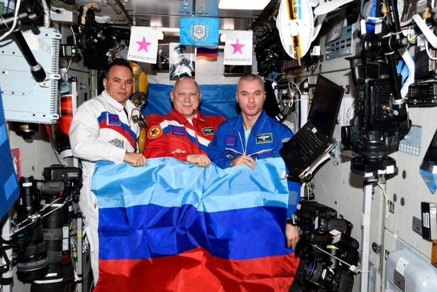 Russian cosmonauts Sergey Korsakov, Oleg Artemyev and Denis Matveev pose with a flag of the self-proclaimed Luhansk People's Republic on the International Space Station.png