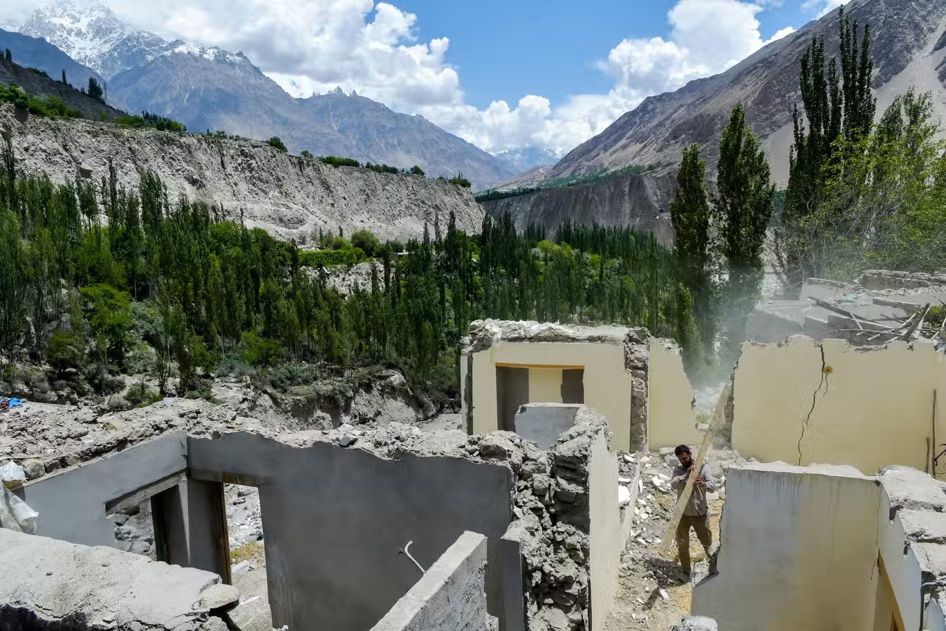 مواطن يزيل حطام منزل متضرر بعد انفجار بحيرة بسبب ذوبان نهر جليدي في قرية حسن آباد في منطقة غلغيت بالتستان الباكستانية في يونيو من العام الحالي (غيتي)
