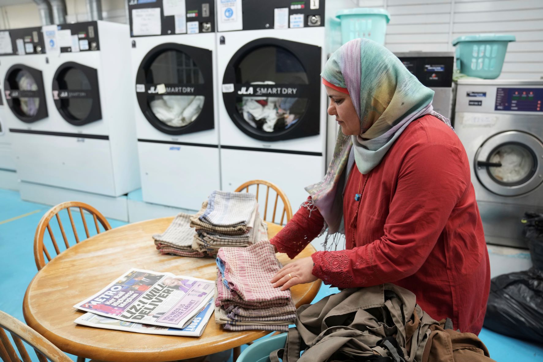 دنيا صالح تطوي غسيلها في مغسلة أوتوماتيكية بمدينة مانشستر بتاريخ 07 سبتمبر 2022. يتوقع أن يعاني مليون بريطاني الفقر هذا الشتاء ما يرفع مستوى العوز في بريطانيا إلى أعلى مستوياته في عشرين سنة حتى لو جمدت الحكومة أسعار الطاقة عن مستوياتها الحالية 