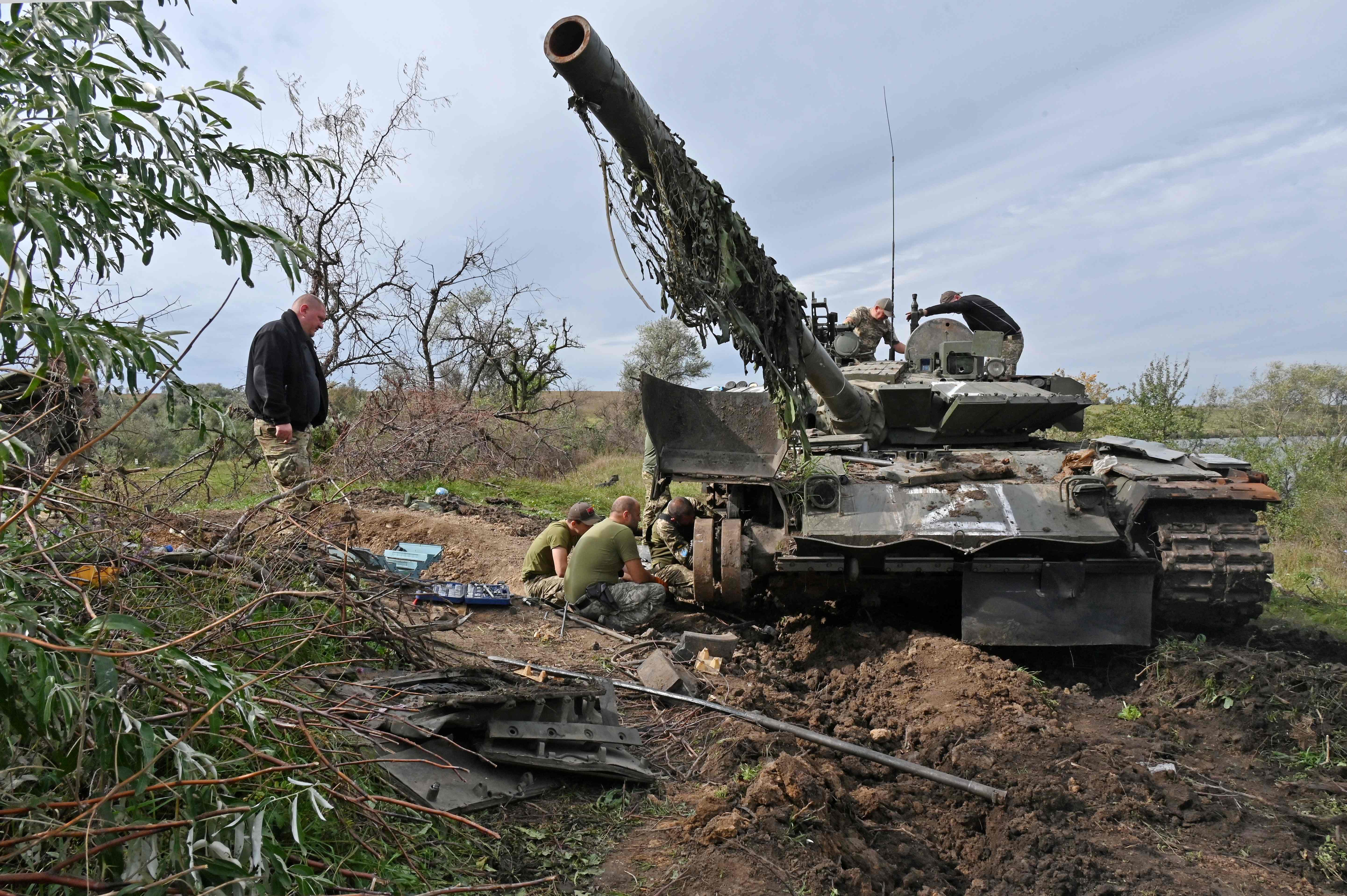 جنود أوكرانيون يعملون على دبابة في 20 سبتمبر 2022 ،تركتها القوات الروسية أثناء انسحابهم في شمال منطقة خاركيف (أ ف ب).jpg