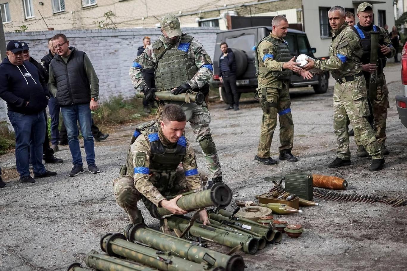 جنود أوكرانيون يقومون بفرز الأسلحة التي خلّفتها القوات الروسية في المناطق التي انسحبت منها (رويترز).jpg