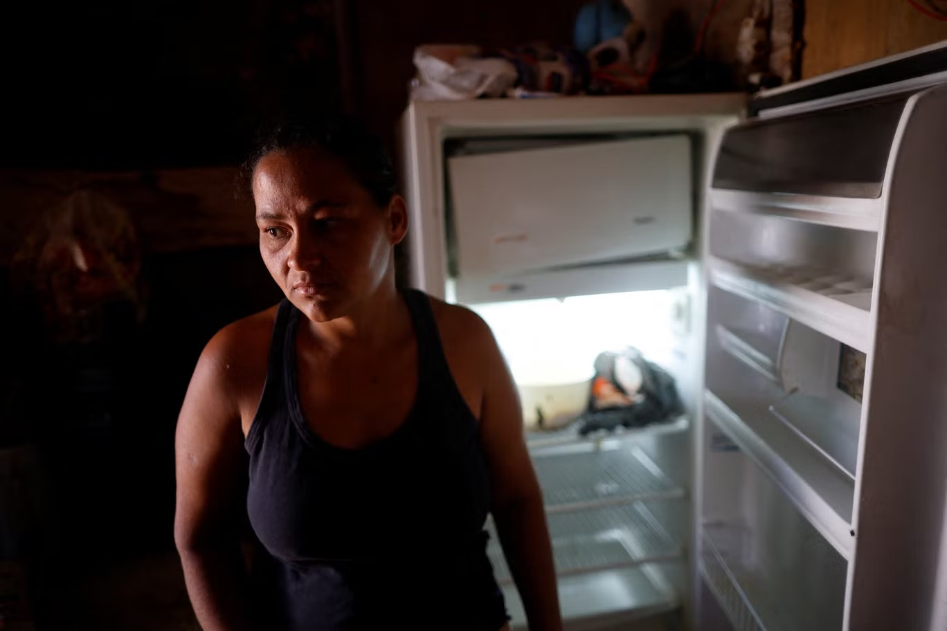 لوسيانا ميسياس دوس سانتوس، 29 سنة، تقف لالتقاط صورة أمام ثلاجتها الفارغة في منزلها في "فافيلا" استروتورال الفقير في العاصمة برازيليا (رويترز)