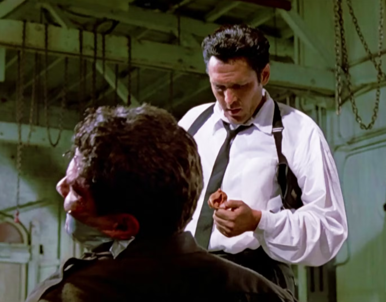 مايكل مادسن يؤدي دور مستر بلوند في مشهد قطع أذن شرطي بفيلم كلاب المستودع الذي أخرجه كوينتين تارانتينو عام 1992 