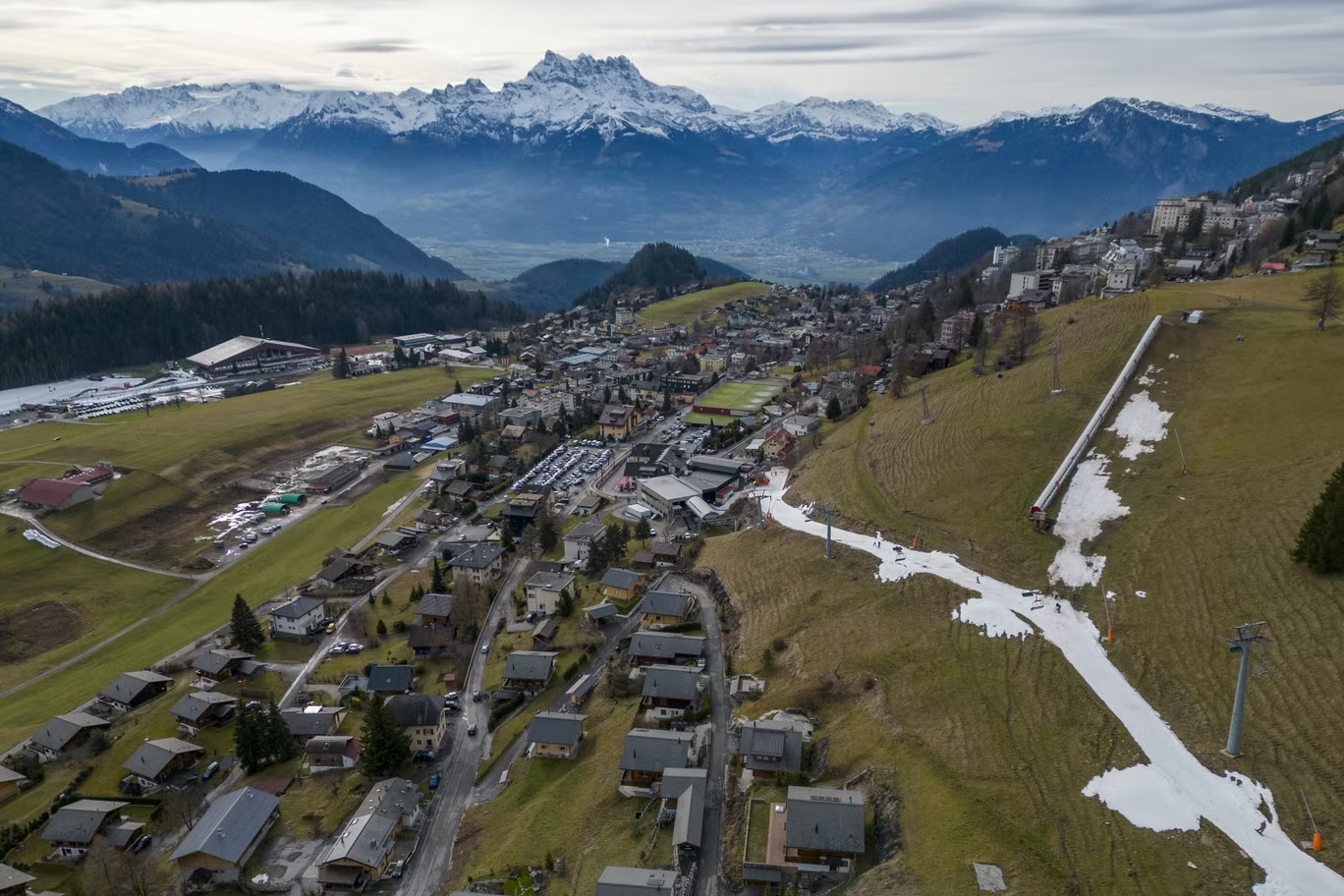 المتزلجون يمرون على طبقة صغيرة من الثلج الاصطناعي وسط درجات حرارة شتاء أكثر دفئاً من المعتاد في جبال الألب في ليسين، سويسرا في 4 يناير (رويترز)