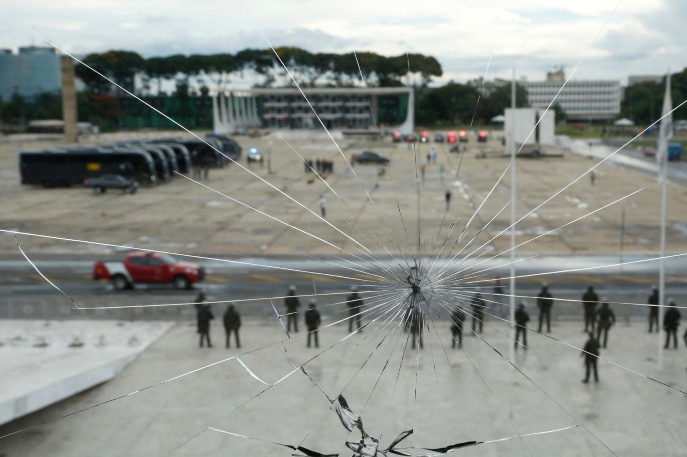 حراس الأمن يشاهدون عبر زجاج نافذة مكسور أثناء وقوفهم أمام قصر بلانالتو خلال تنصيب سونيا غيايارا وزيرة لشؤون الشعوب الأصلية في برازيليا بتاريخ 11 يناير 2023 (أ ف ب)