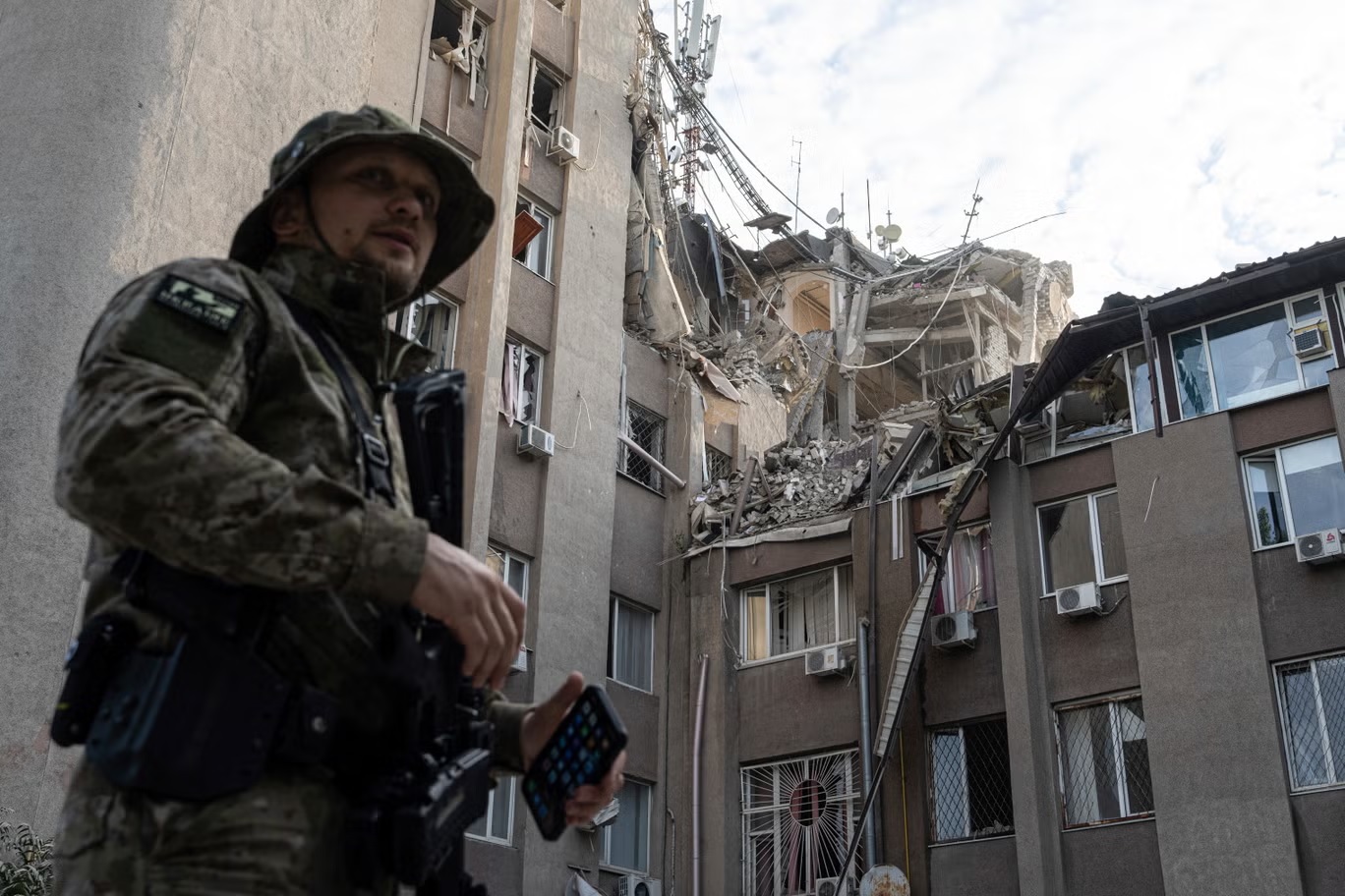جندي أوكراني يقف أمام مبنى تضرر كثيراً في غارة جوية روسية، في خيرسون يوم الخميس (أ ب)
