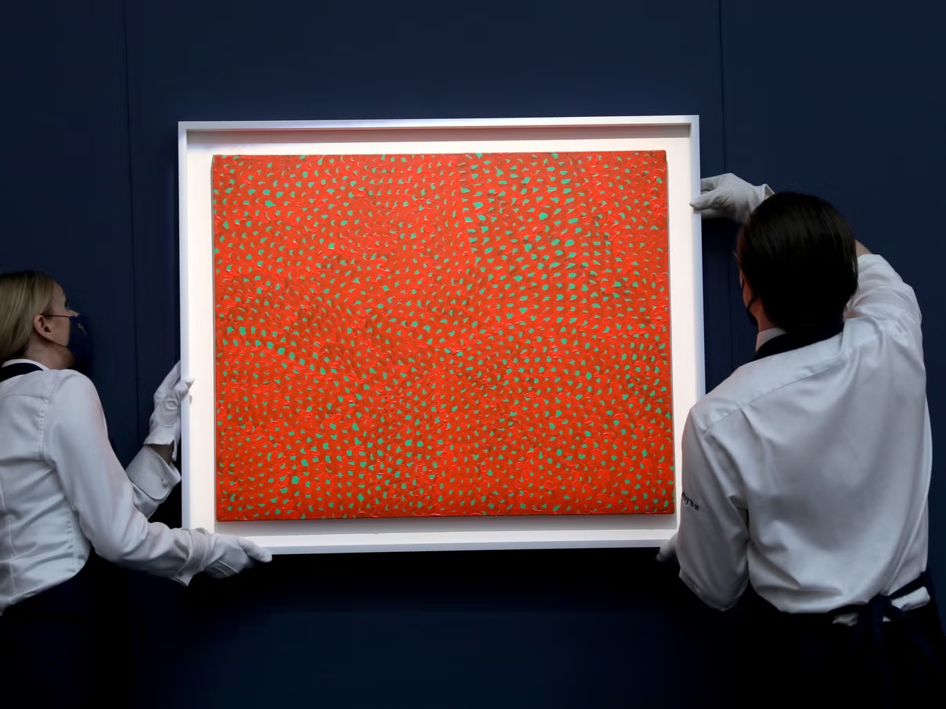 "شبكات لا نهائية (إكس واي زي)" ليايوي كوساما يحملها مساعدان في دار سوذبيز للمزادات العلنية عام 2021 (غيتي لمصلحة سوذبيز)