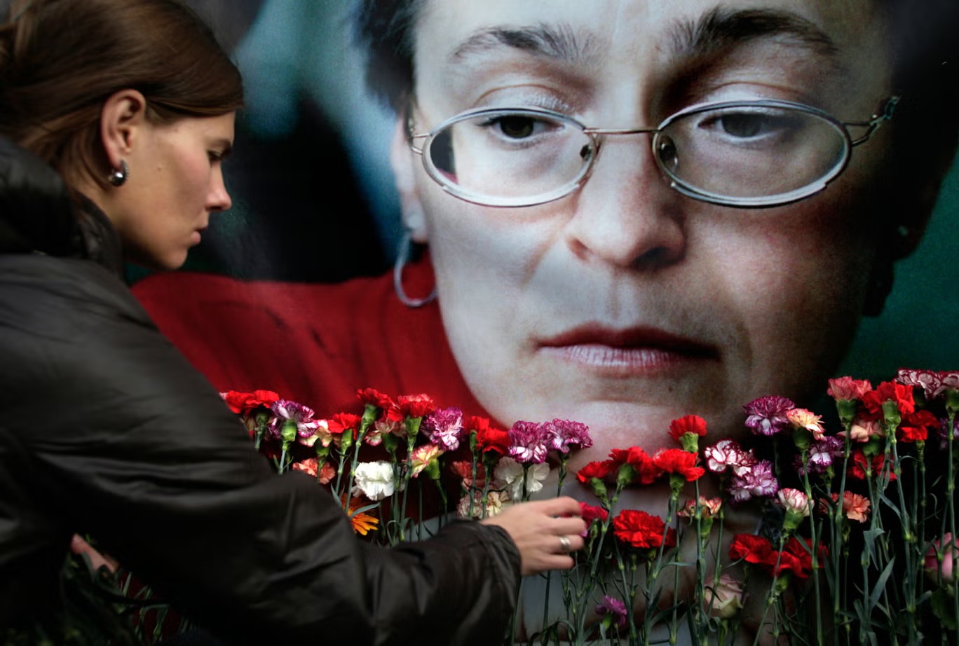 امرأة تترك زهوراً أمام صورة الصحافية آنا بوليتكوفسكايا التي ماتت مقتولة (أ ب)