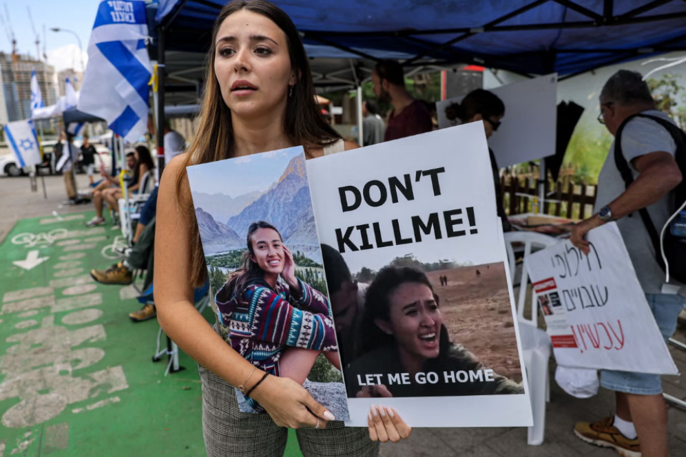 صديقة للطالبة الإسرائيلية نوا أرغماني، إحدى الرهائن الإسرائيليين الذين تحتجزهم حماس، تقف مع لافتة تظهر وجهها