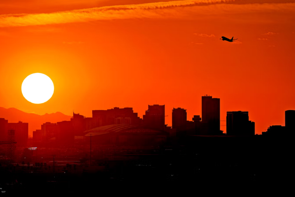 طائرة تحلق في سماء المغيب فوق مدينة فوينكس التي تمتد إلى ماريكوبا المنطقة الأميركية الحضرية الأشد سخونة والتي سجلت الرقم القياسي للحرارة في الـ 19 من أكتوبر (تشرين الأول) 2023 بالنسبة إلى الوفيات السنوية المتصلة بالحر الشديد 