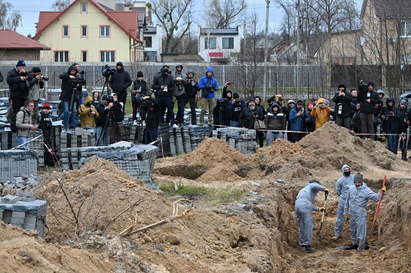 صحافيون يتجمعون لتصوير انتشال جثث مدنيين من مقبرة جماعية في مدينة بوتشا الأوكرانية (أ ف ب).jpg