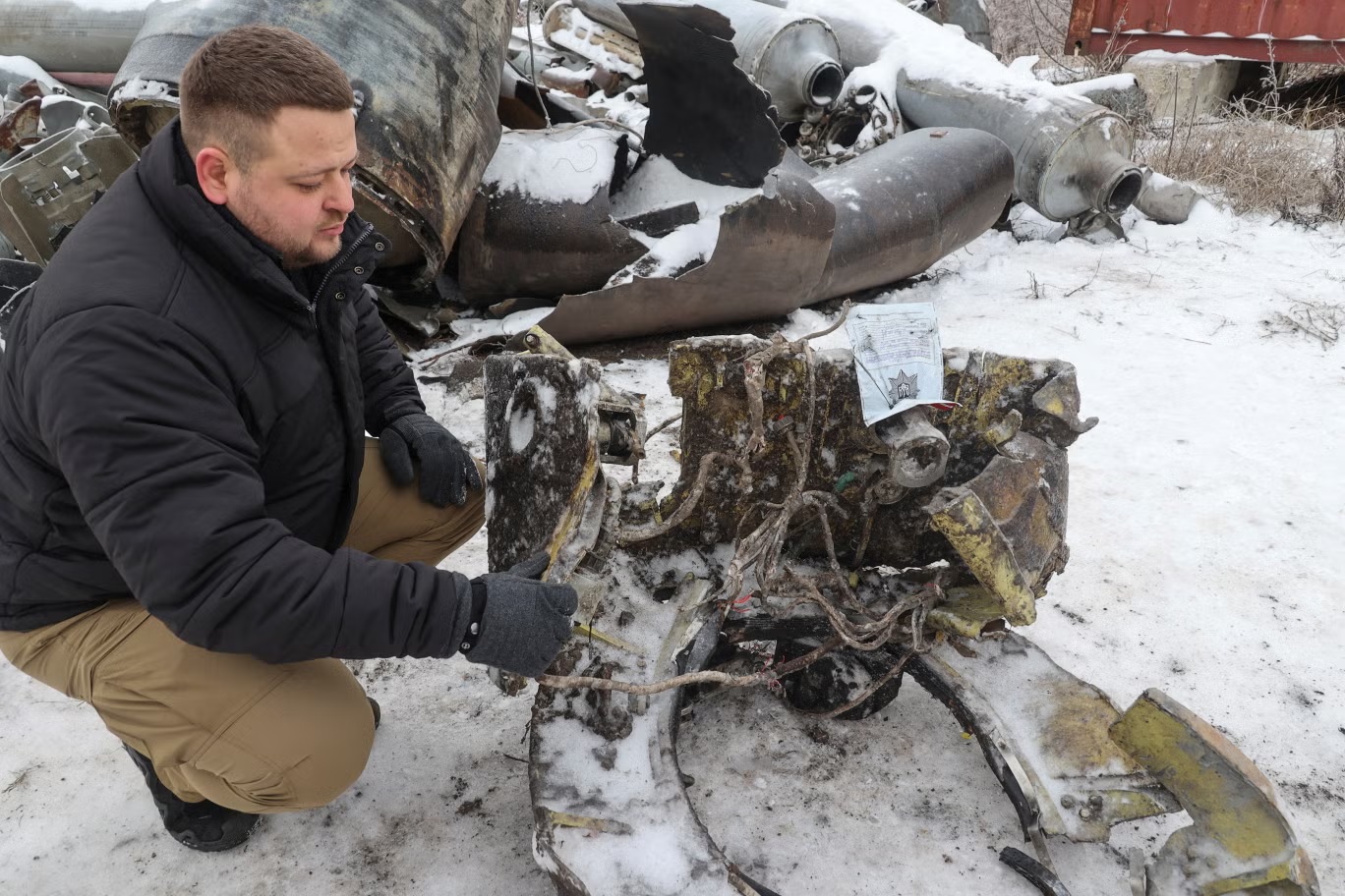 ممثل من مكتب المدعي العام الأوكراني يظهر أجزاء من صاروخ مجهول الهوية، تعتقد السلطات الأوكرانية أنه صنع في كوريا الشمالية واستخدم في ضرب خاركيف (رويترز)