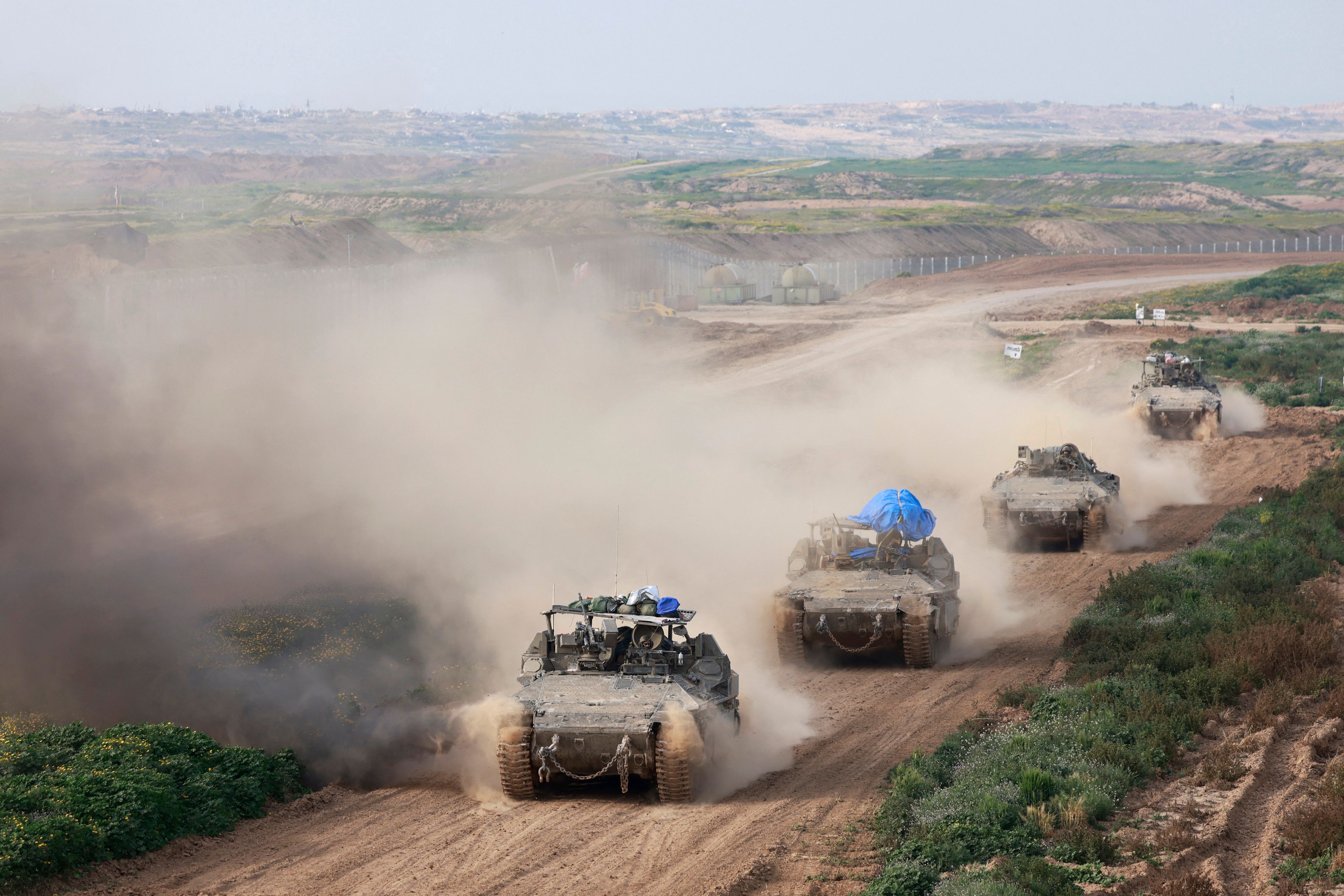 صورة مأخوذة من إسرائيل بالقرب من الحدود مع قطاع غزة تظهر دبابات الجيش الإسرائيلي وهي تخرج من غزة في فبراير 2024 (أ ف ب)