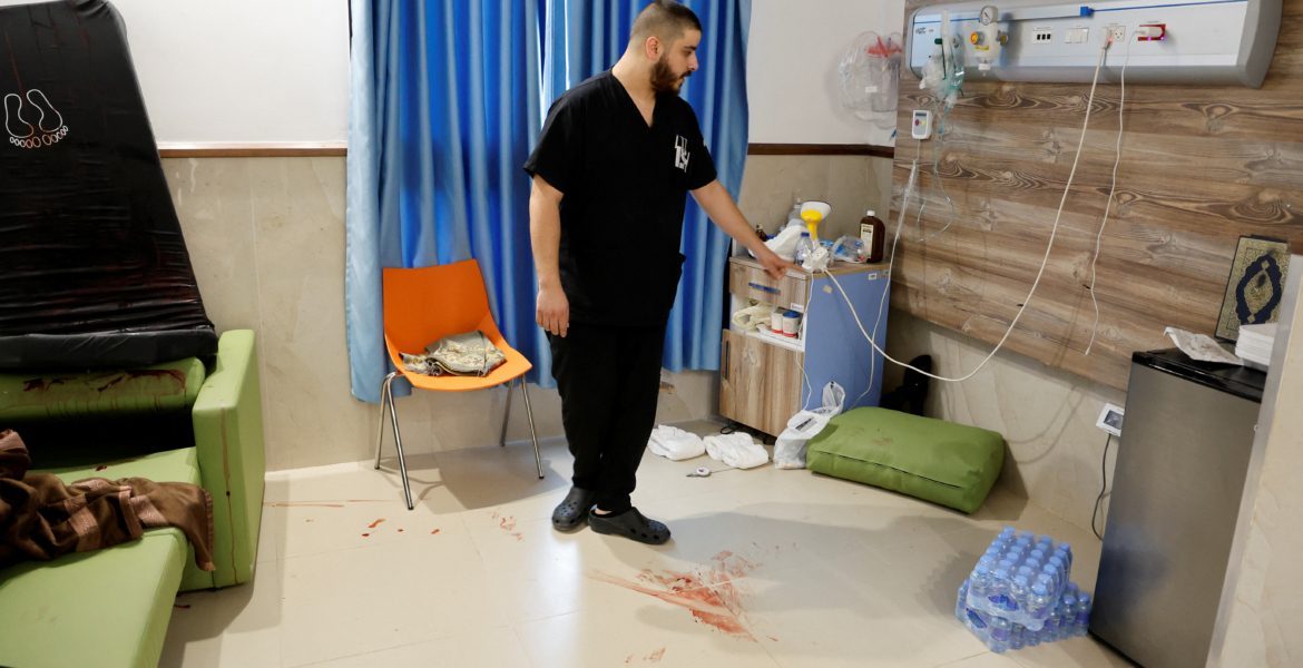 فرد من الطاقم الطبي يقف بجوار بقع الدم في الموقع الذي اغتالت فيه الفرقة ثلاثة فلسطينيين خلال غارة على مستشفى ابن سينا في جنين (رويترز)