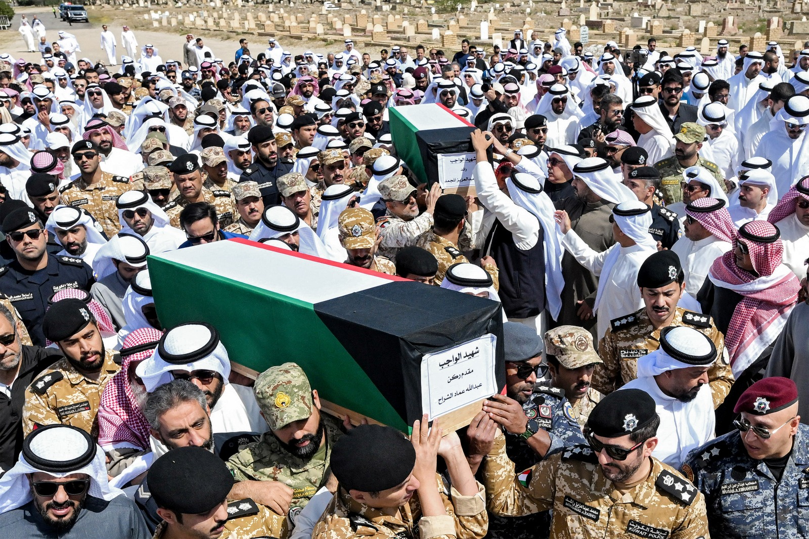  رجال شرطة كويتيون يحملون نعشي حارسي حدود قُتلا أثناء أداء الواجب، خلال مراسم جنازة رسمية في مقبرة الصليبخات غرب مدينة الكويت، 9 مارس 2026.