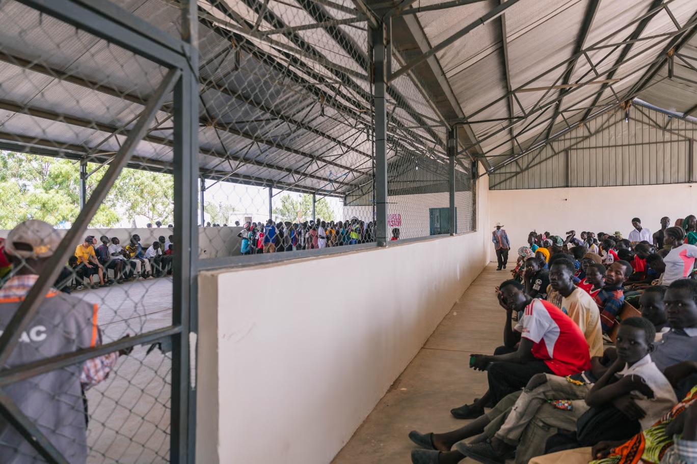 سكان مخيم كالوبيي للاجئين يصطفون انتظاراً لتوزيع المواد الغذائية (سارة وايسوا/الصليب الأحمر البريطاني)