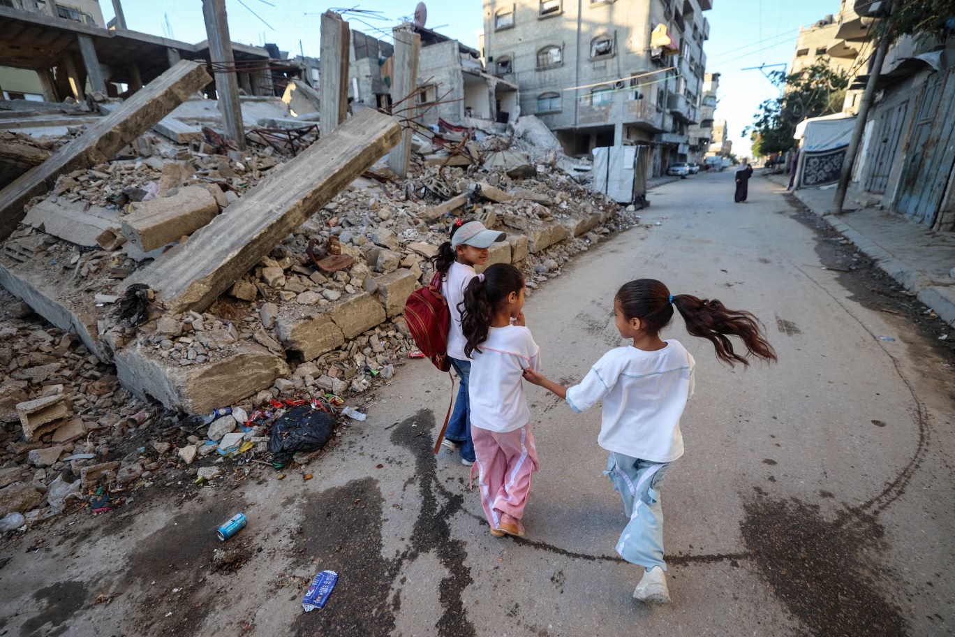أطفال فلسطينيون في طريقهم إلى المدرسة عبر حي البريج المدمر وسط قطاع غزة (أ ف ب/غيتي)